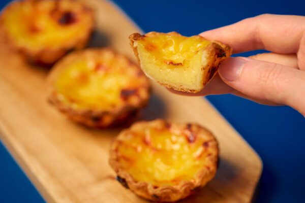 横浜エッグタルトが３つ並べられて、１つを手で持っている様子